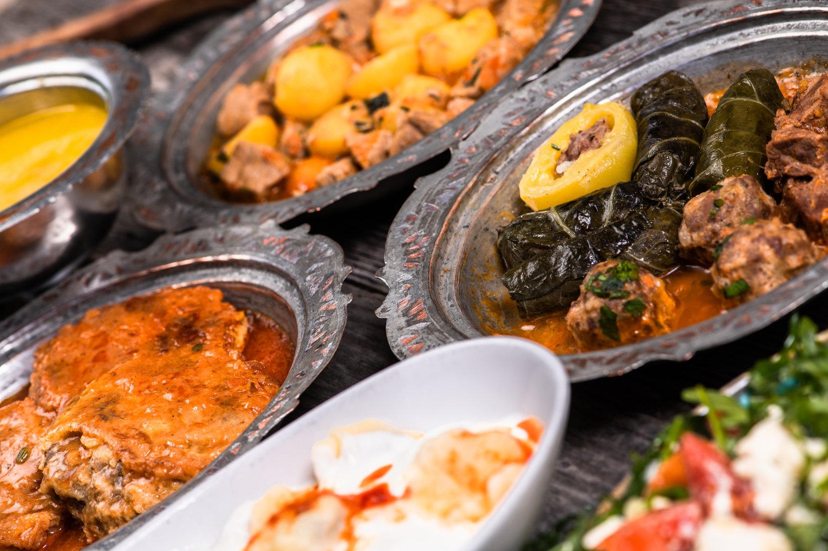 Eid Mubarak Traditional Ramadan Iftar dinner. Assorted tasty food in authentic rustic dishes on wooden blue background. Turkish Bosnian food meat kebab, pita, Sarma, klepe, sogan dolma.